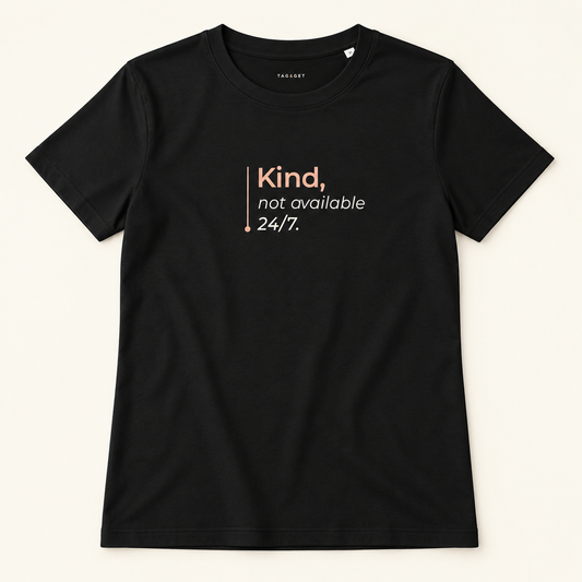 T-shirt preta Tag&Get com a frase “Kind, not available 24/7.”, vista de frente sobre fundo creme.