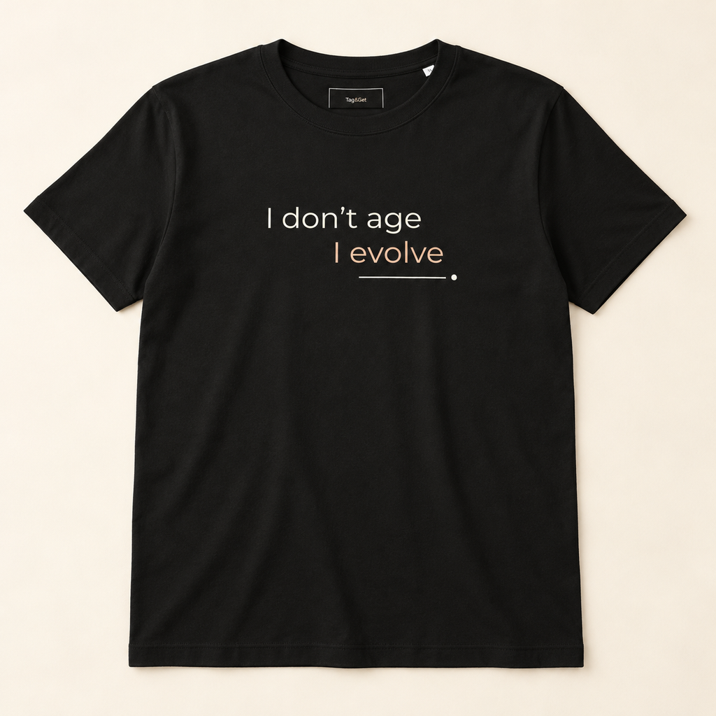 T-shirt preta «I don't age, I evolve», vista de frente sobre fundo creme.