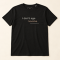 T-shirt preta «I don't age, I evolve», vista de frente sobre fundo creme.