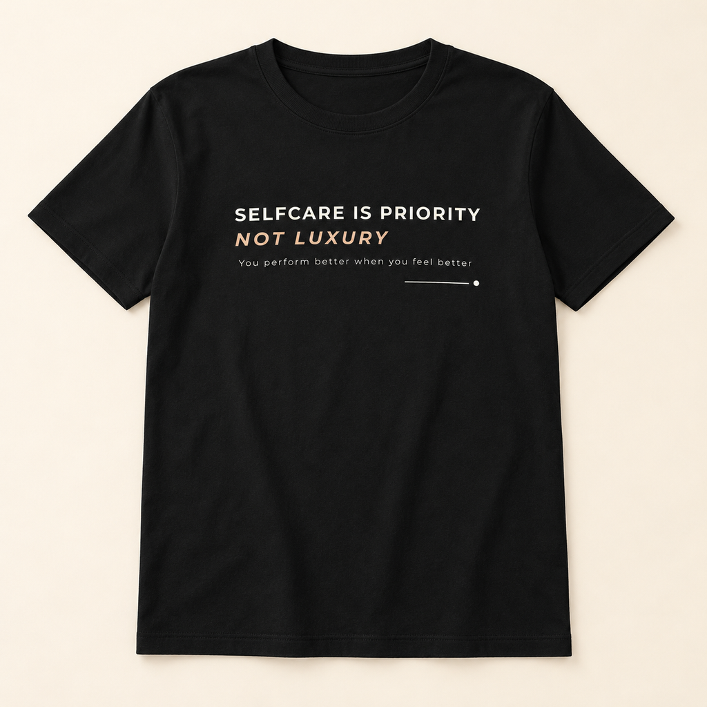 T-shirt preta «Selfcare is priority, not luxury», vista de frente sobre fundo creme.