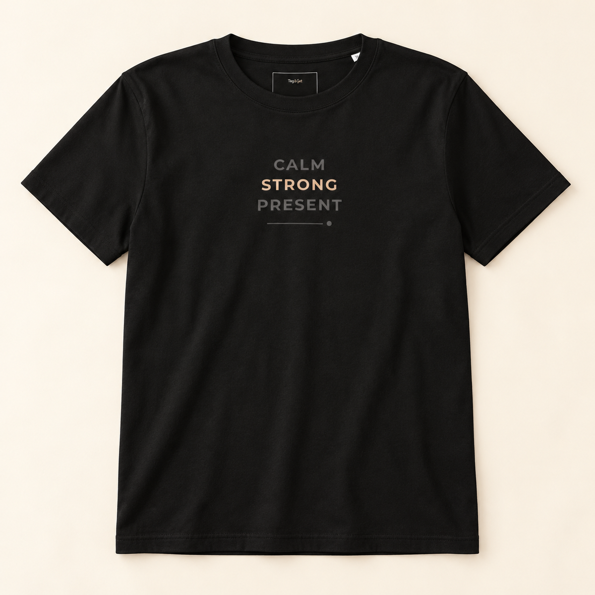 T-shirt preta «Calm. Strong. Present.», vista de frente sobre fundo creme.