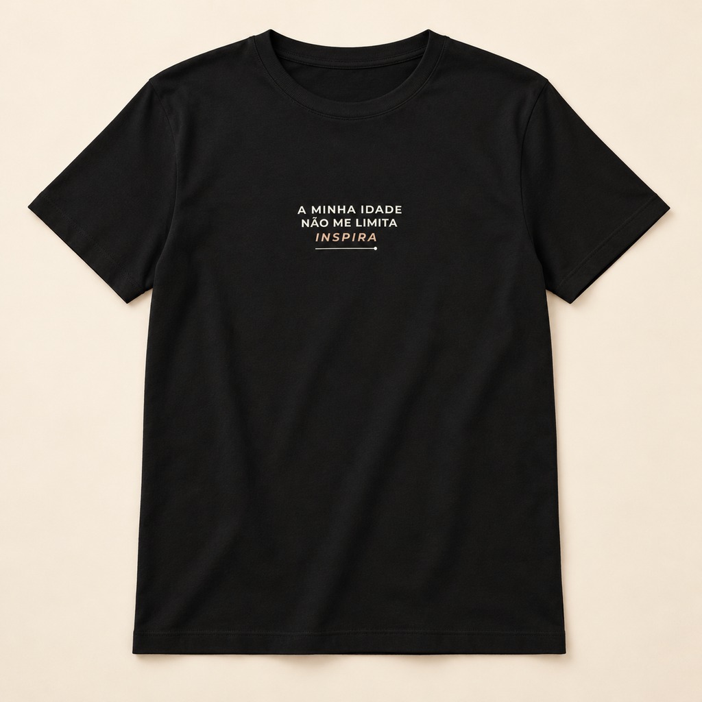 T-shirt preta «A minha idade não me limita, inspira», vista de frente sobre fundo creme.