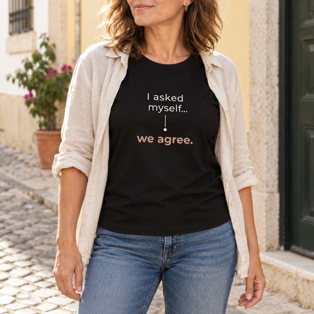 Mulher com a T-shirt preta “I asked myself... we agree.”, camisa clara aberta e jeans numa rua portuguesa; imagem gerada com estética UGC.
