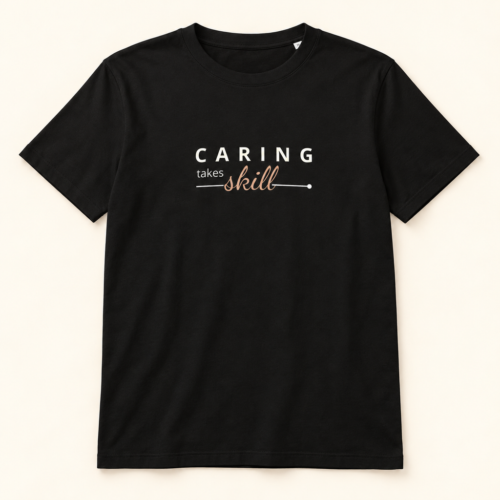 T-shirt preta Caring Takes Skill, vista frontal completa sobre fundo creme.