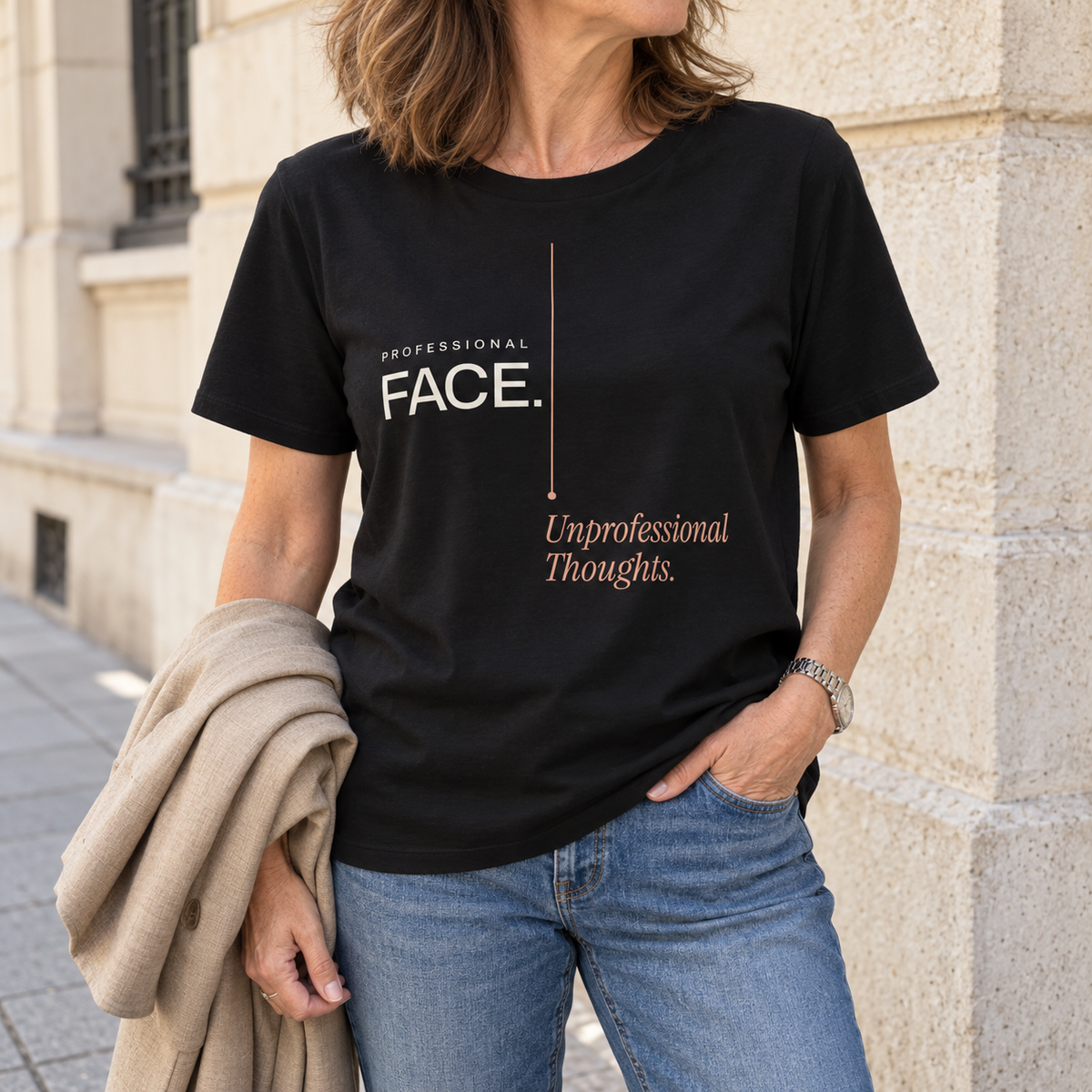 Imagem gerada com estética UGC: mulher com T-shirt preta Professional Face. Unprofessional Thoughts. com jeans e blazer bege no braço numa rua.
