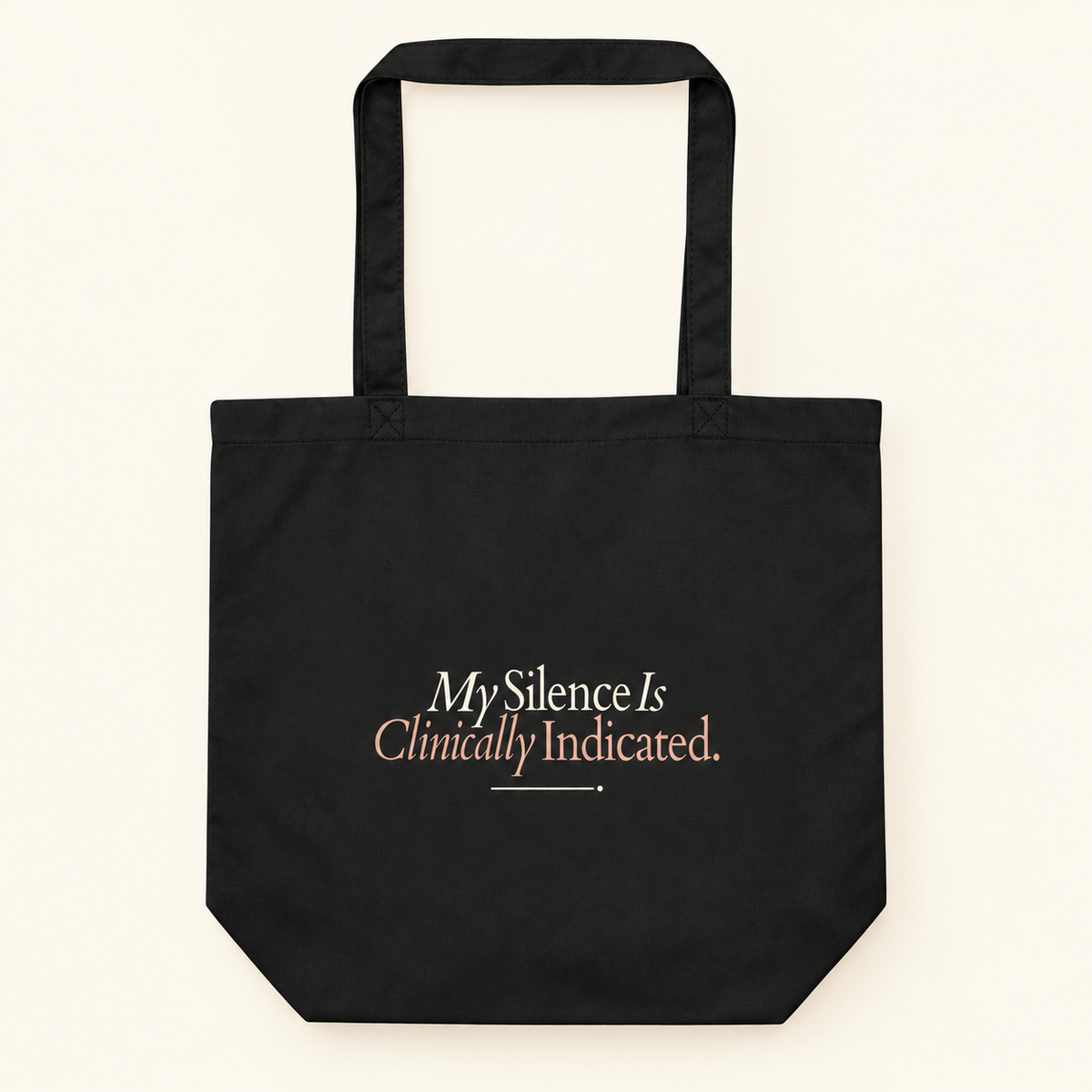 Tote bag preta com a frase “My Silence Is Clinically Indicated.”, vista de frente e completa sobre fundo creme.