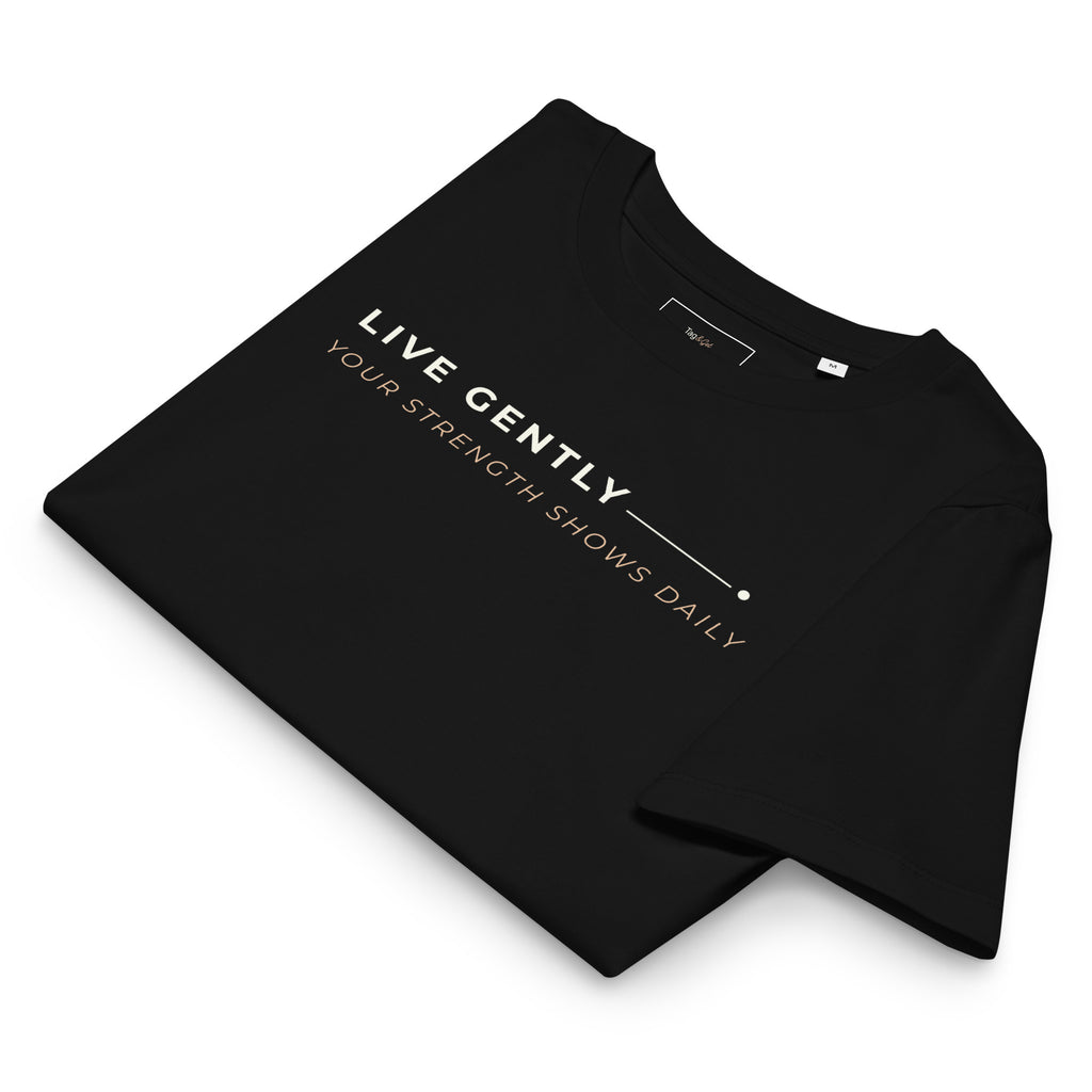 T-shirt preta dobrada, com o estampado «Live gently, your strength shows daily» visível.